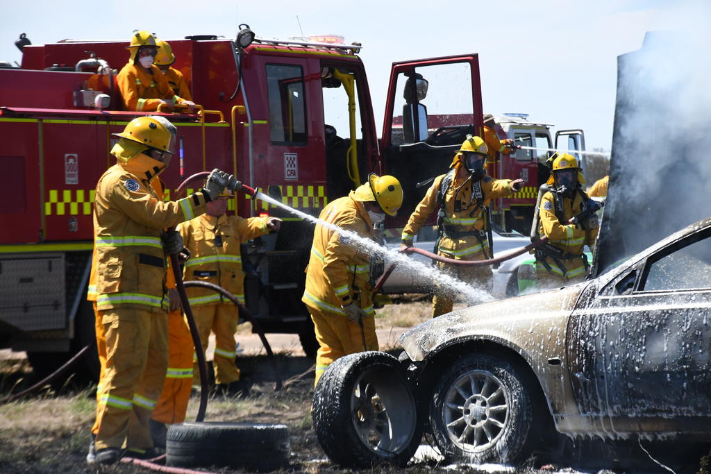 District firefighters attempt to extinguish one of 19 cars burnt in the Lah fire. Photo: DAVID WARD