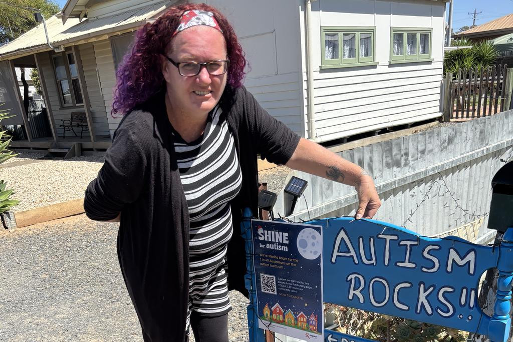 Kerry Torney with her homemade sign with a poster with a QR code that can be scanned to donate to Shine for Autism. Photo: CAITLIN MENADUE