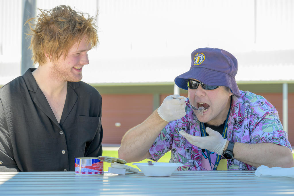 Horsham College teacher Nick Shirrefs tastes surströmming, the world's smelliest fish, alongside his former student Louis Willemsen in the college grounds.