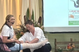 Casey Koch and her assistant demonstrate how to apply a bandage to a potential snake bite on the leg, explaining the steps as they go. Photo: CAITLIN MENADUE