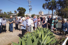Community members come together to watch the unveiling of the plaque.