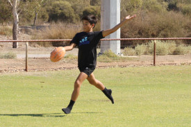 Theo Badua is about to kick a ball.