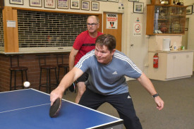 Craig Byron reaches for a backhand return with partner Jason Robinson watching on.