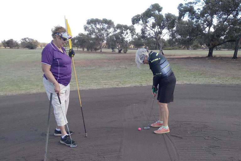 Helen Fisher lines up her putt as Joy Mathews tends the flag on the 9th hole.