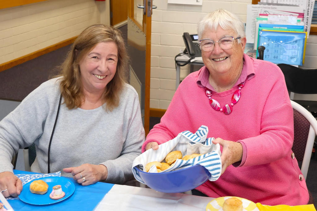 Ann Jensz, right, offers a scone to Jill Gooding.