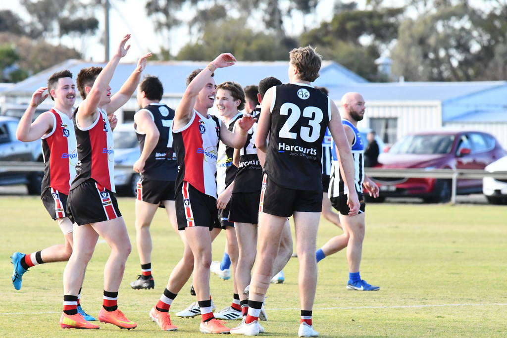 ALL SMILES: Saints from left, Mitch Martin, Gage Wright, Jackson Davidson, get around Cody Bryan after he kicked a goal in the last quarter against the Burras.
