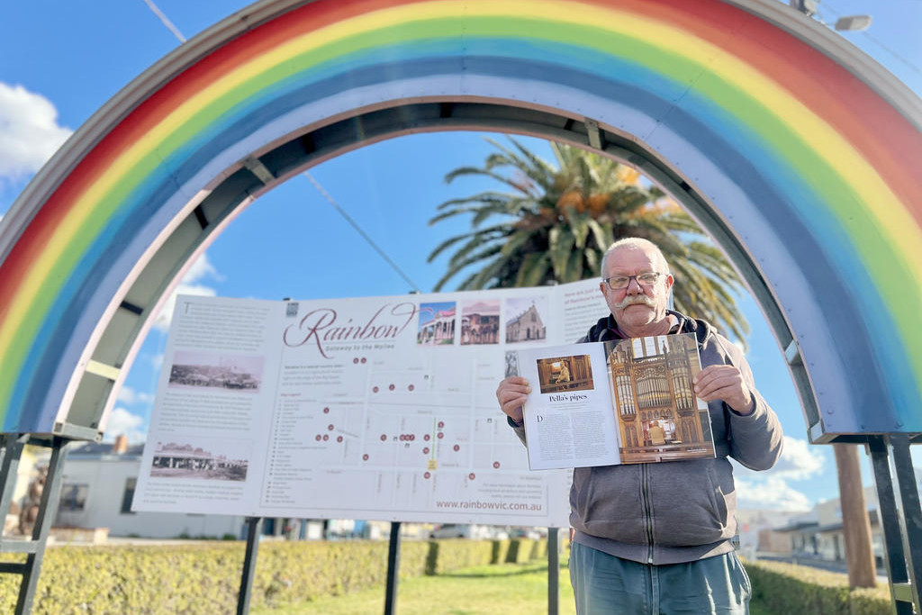 Mal Drendel pictured with RM Williams magazine in front of the town's sign. Photo: TAYYAAB MASROOR