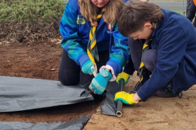 Cub leader Jess helping Tanner with the weed mat.