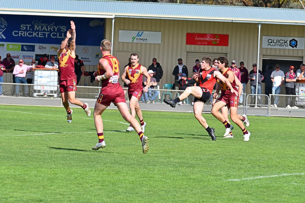 Stawell forward Cody Driscoll sends the ball deep into the Warriors' forward 50, despite strong pressure from the Warrack Eagles defenders.