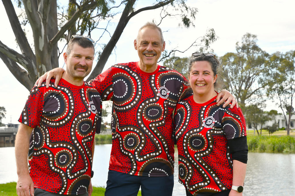 Wimmera River parkrun event directors Andrew Sostheim (left) and Jackie Exell (right), and Dimboola Dash event organiser Brian Haddy (middle) showcase the Dimboola Dash Running Festival shirt, designed by Imigo Dawn.