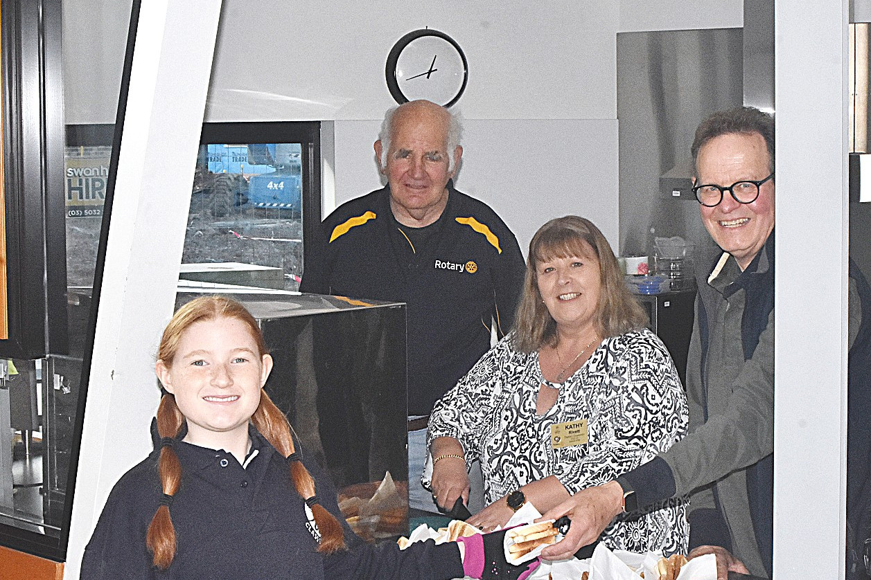 TOGETHER: Rotary members Tony Gregson, District Governor Kathy Rivett and president John Tonkin give jam on toast to Year 6 student Maddie who comes in regularly for Warracknabeal Primary School breakfast clubs.