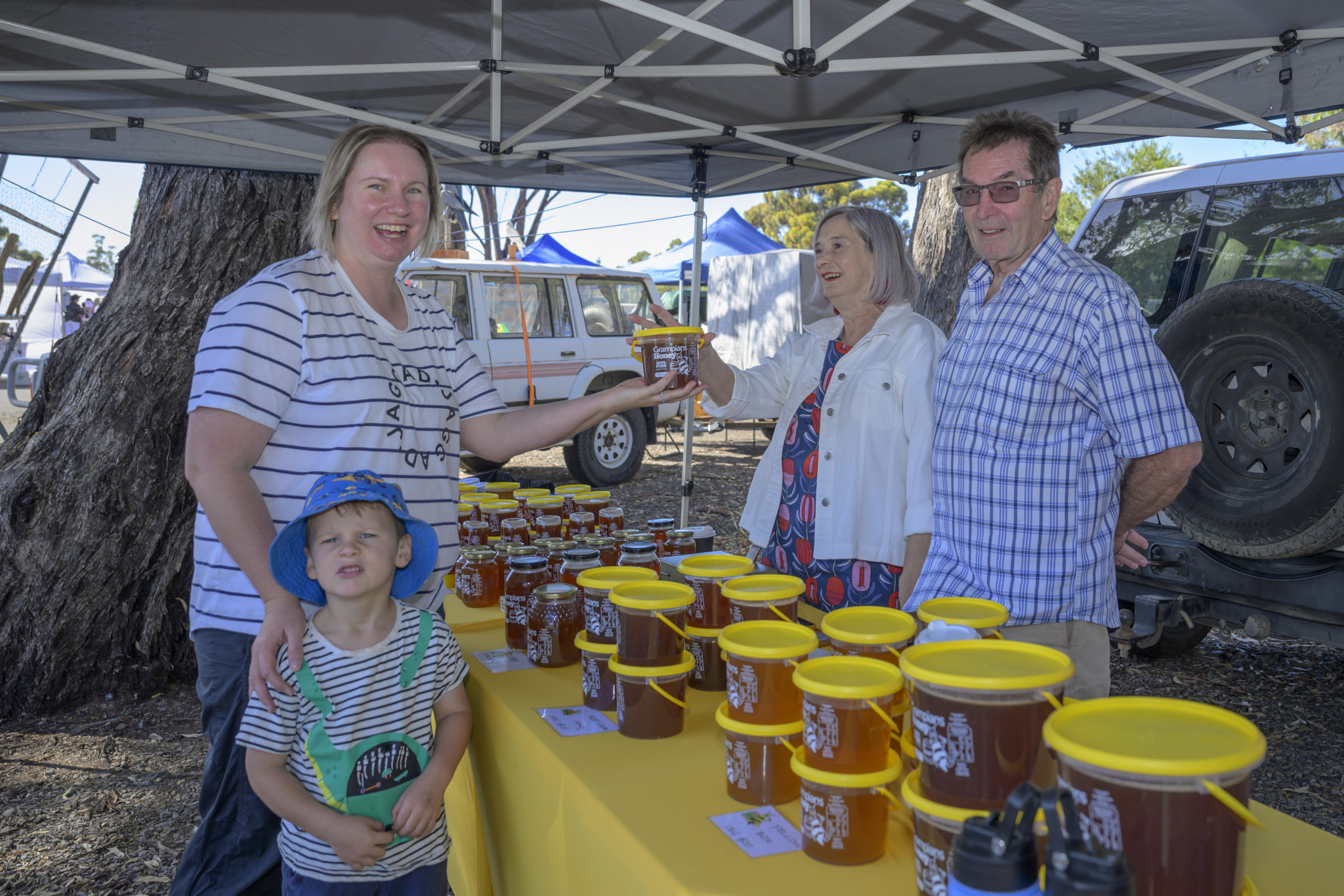 Alison Hicks and Miles Hicks buy honey from Marion and Steve Sostheim. Photo: ROBIN WEBB