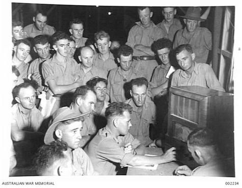 Members of the 2/8 Australian Infantry Battalion, AIF, listen to a radio broadcast