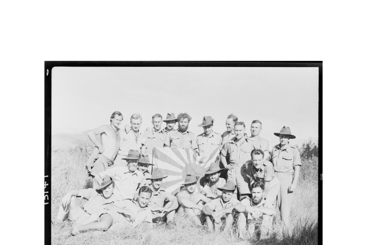New Guinea members of B Company, New Guinea Volunteer Rifles, proudly display a Japanese flag captured at Mubo on July 21 1942.