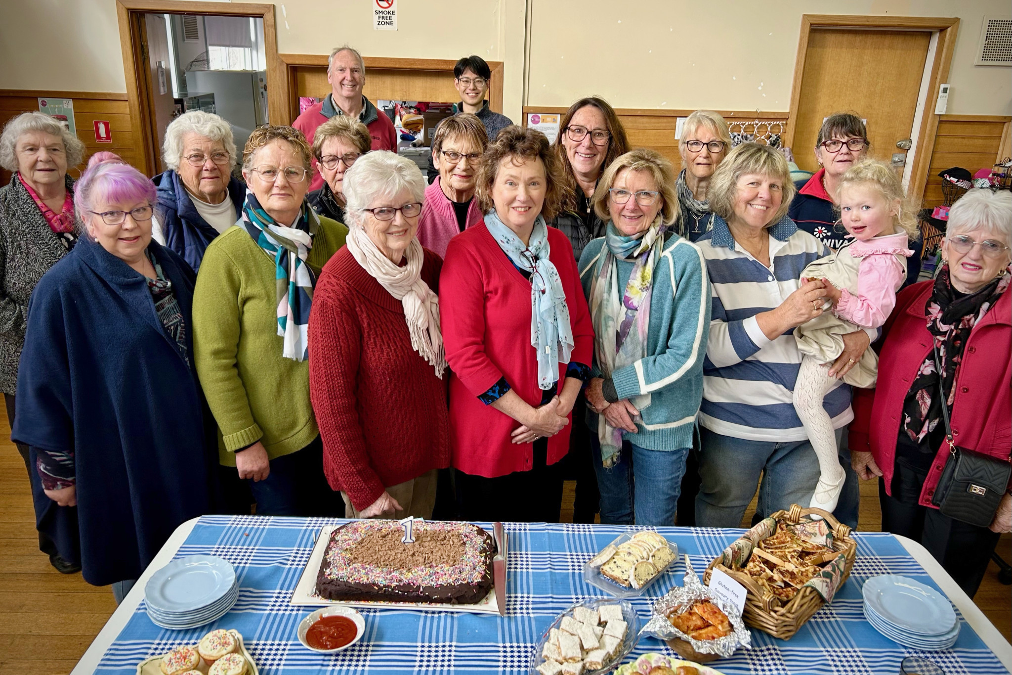 The four members of the management committee in the front row, Robyn Jewell, Kerryn Dyer, Diane Eastwood, and Carolyn Howe, with her granddaughter, Eloise, celebrating the day with others.