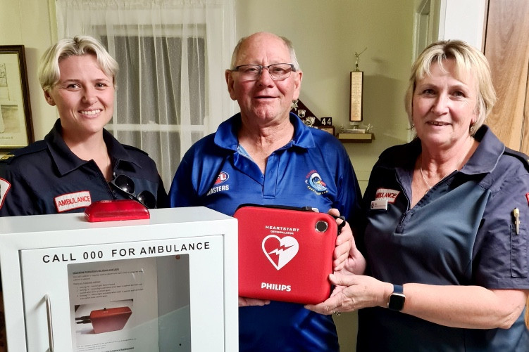 Ambulance Victoria community officers Sue and Megan Watts and Warracknabeal Lions Club president Maurie Parsons prepare to install the new automated external defibrillator (AED) at Lion's Park