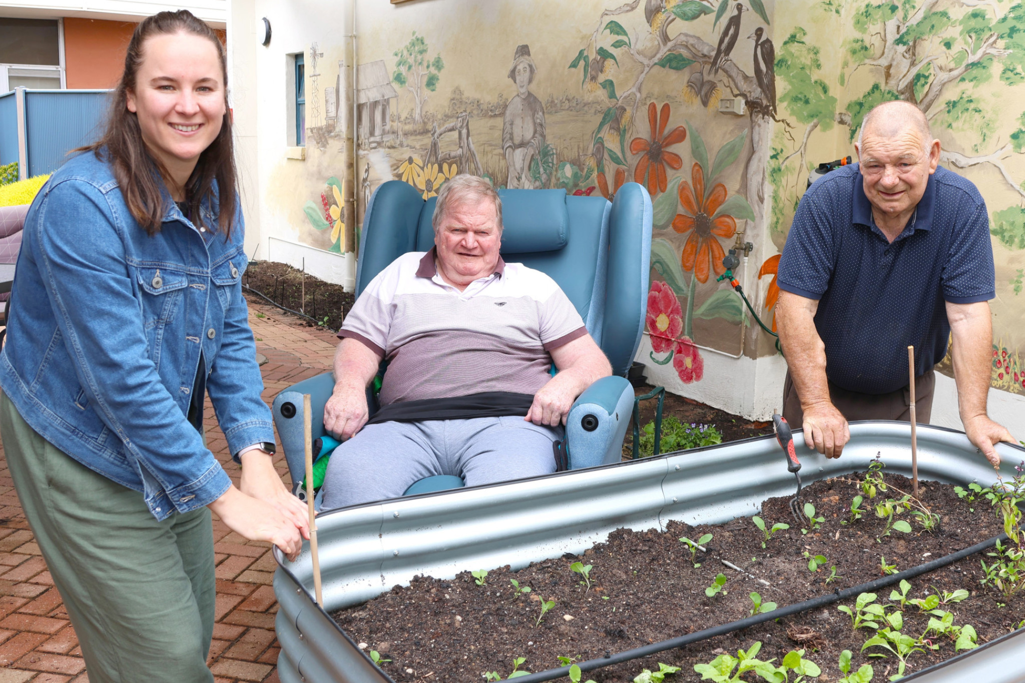 Dimboola Meaningful Life coordinator Megan Naylor with residents Graeme and the late David in a section of the Bretag garden. CREDIT Grampians Health