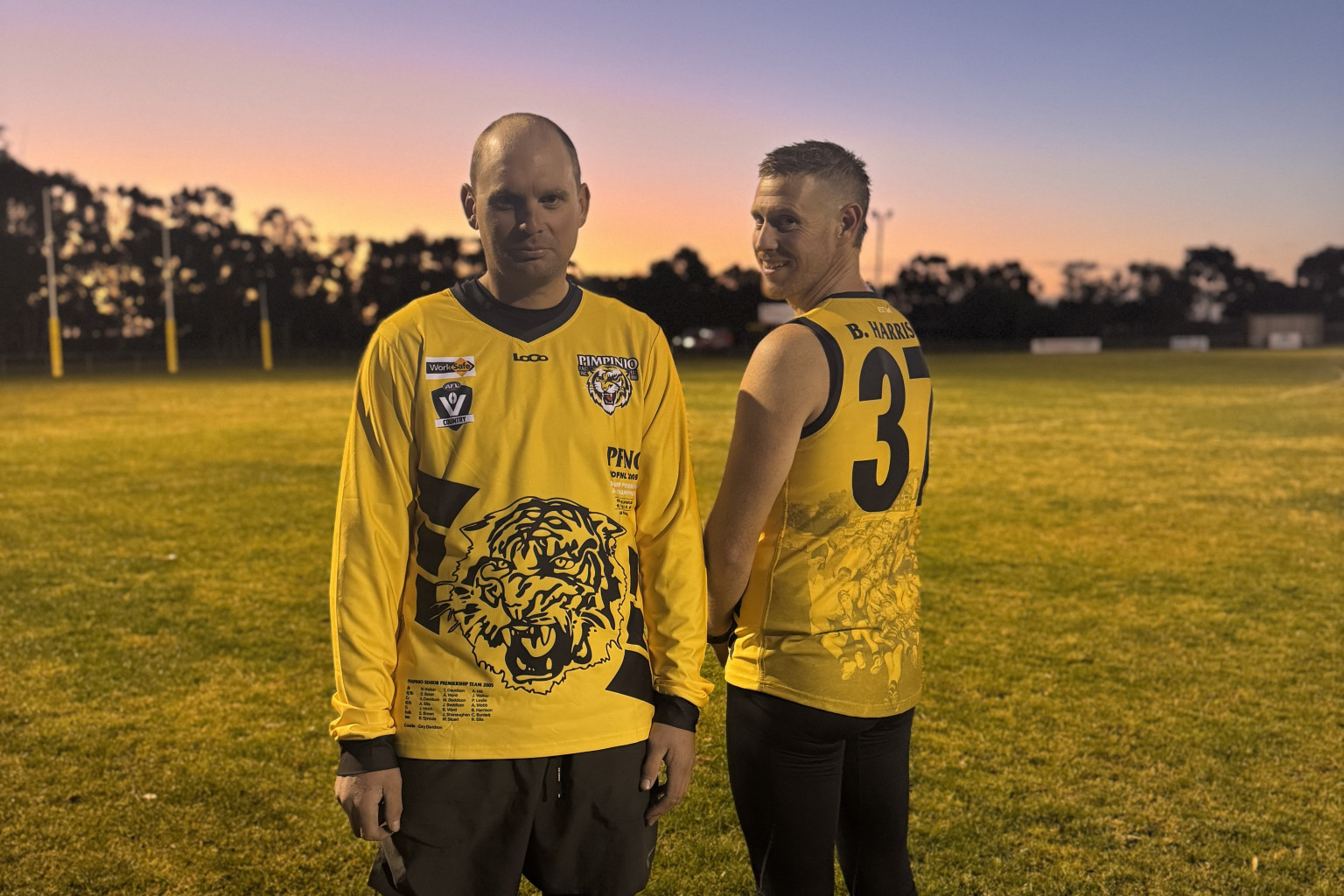 Current Pimpinio players Daniel Baker and Kyle Dumesny try on the commemorative jerseys the men's senior football team will wear on Saturday. Baker was also part of the 2005 premiership side.