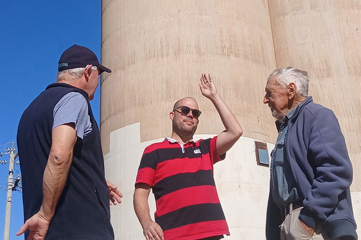 Bernard Young, James Voller and Llew Schilling in front of the silo at Rainbow during the artist's latest visit.