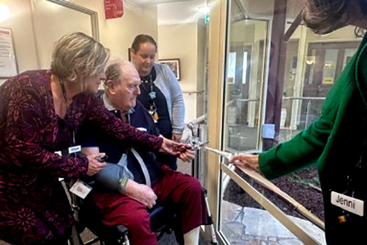 Hopetoun Nurse Unit Manager Alison Fischer and Campus Manager Angela Naylor assist resident Frank White in cutting the ribbon.